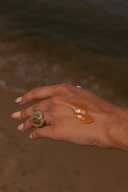 Top of girl's hand with orange balm on the back of it. 