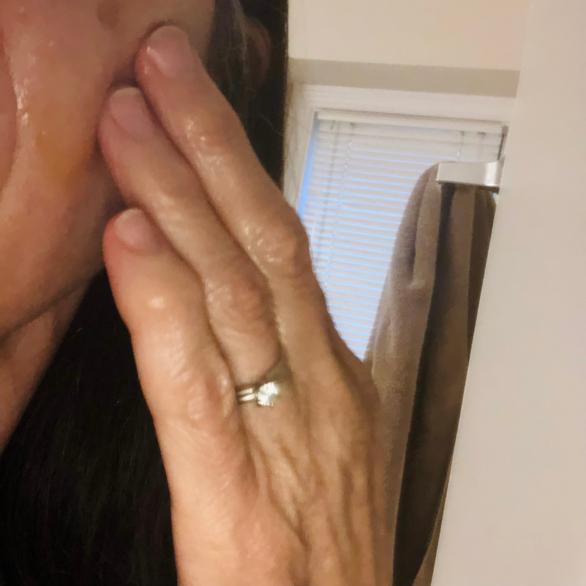 Customer's hand touching her face, applying serum. 