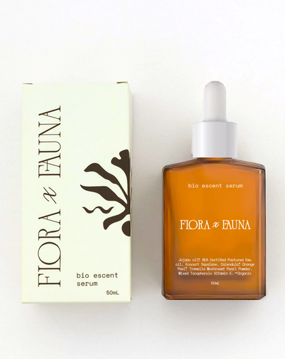 Cream product box with Flora x Fauna logo and brandmark on it, laying to the left of a 50 ml bottle of bio escent serum. 
